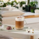 Капучино с цветами и кофейной капсулой на столе.