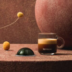 Чашка кофе Nespresso и капсула на фоне.