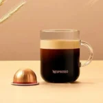 Кружка кофе с капсулой Nespresso на столе.