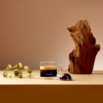 Чашка кофе с капсулой Nespresso на столе.