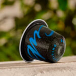 Кофейная капсула на фоне зелени